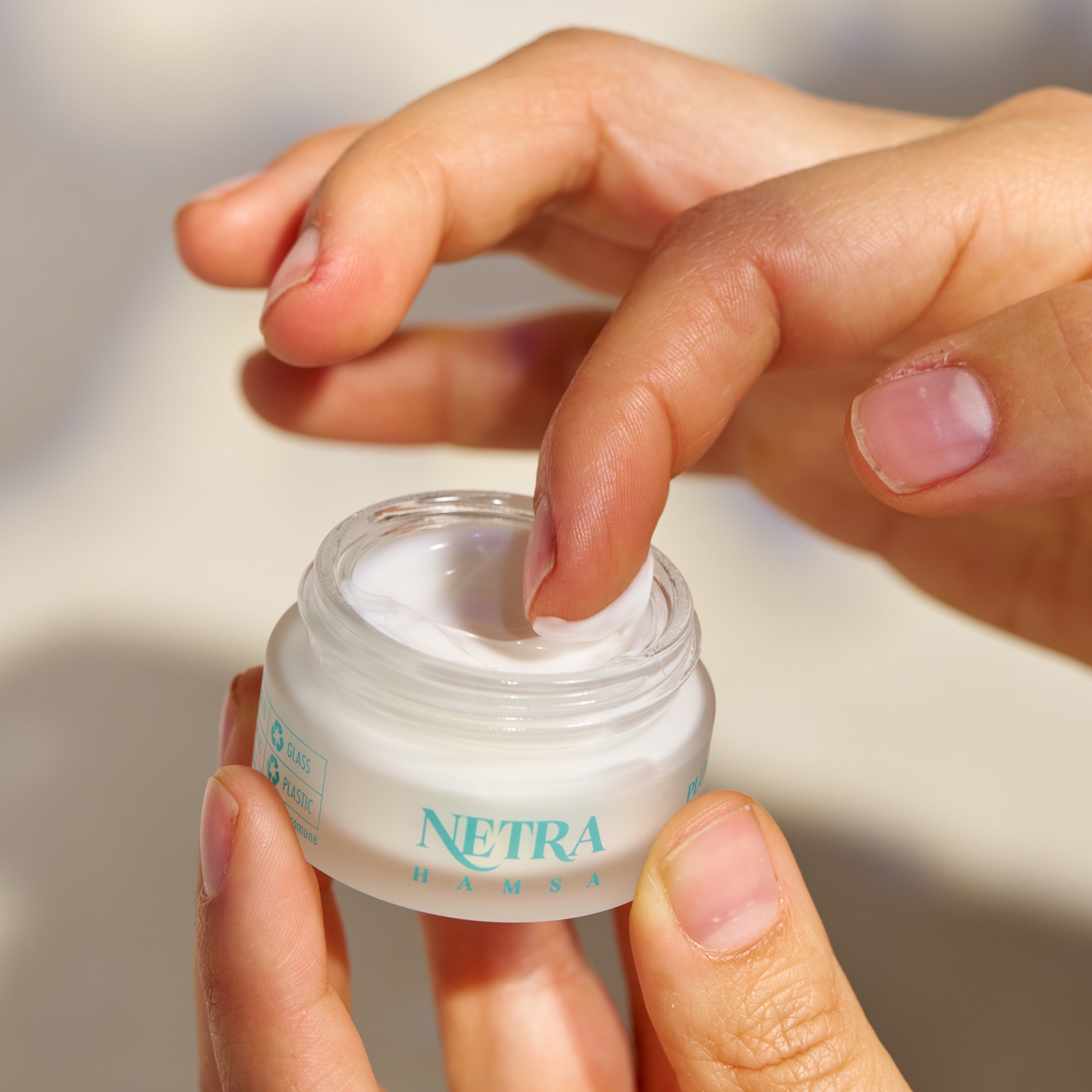 Person holding a jar of Netra cream with a blurred background
