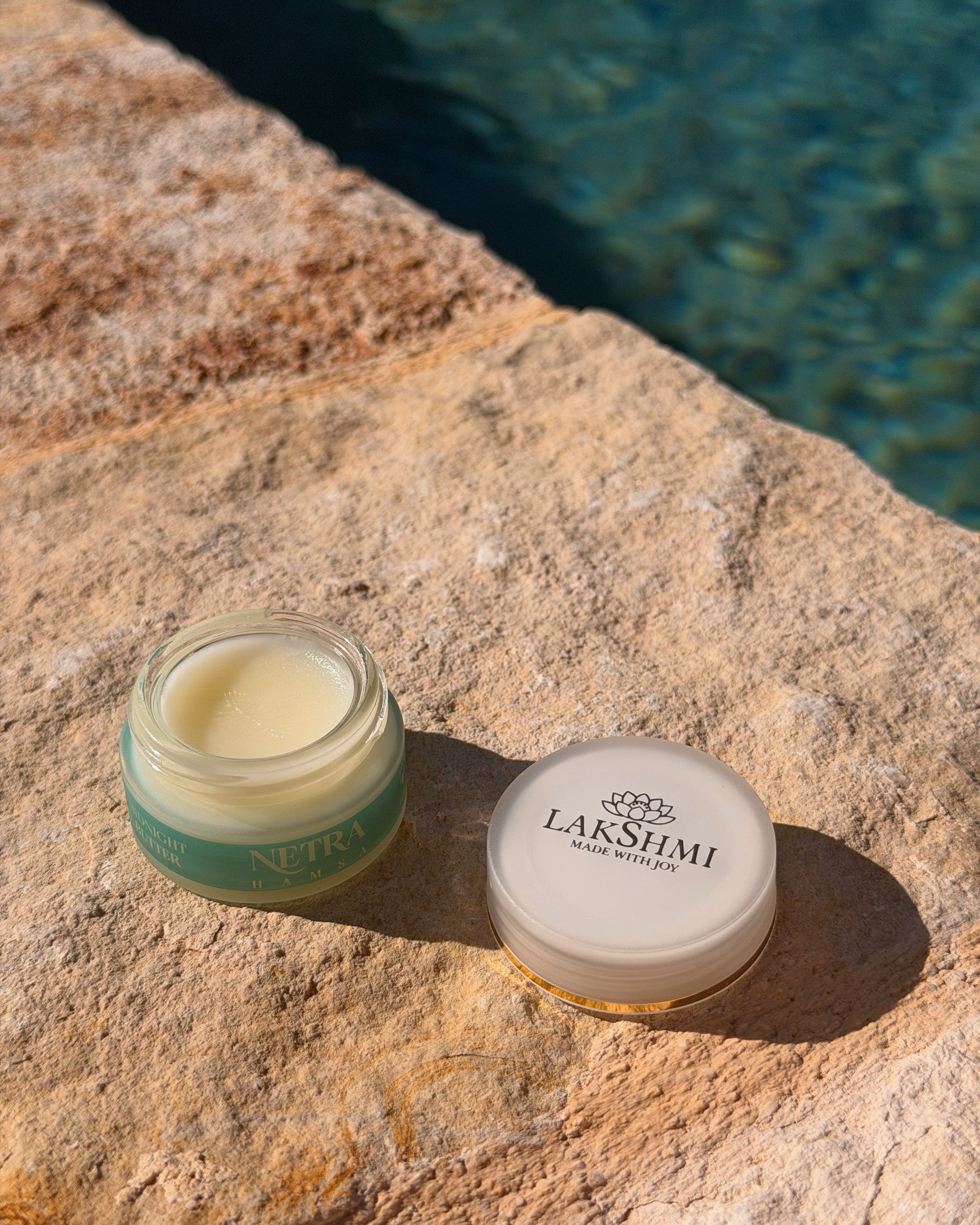 Lakshmi NETRA Midnight Butter open jar on stone by water